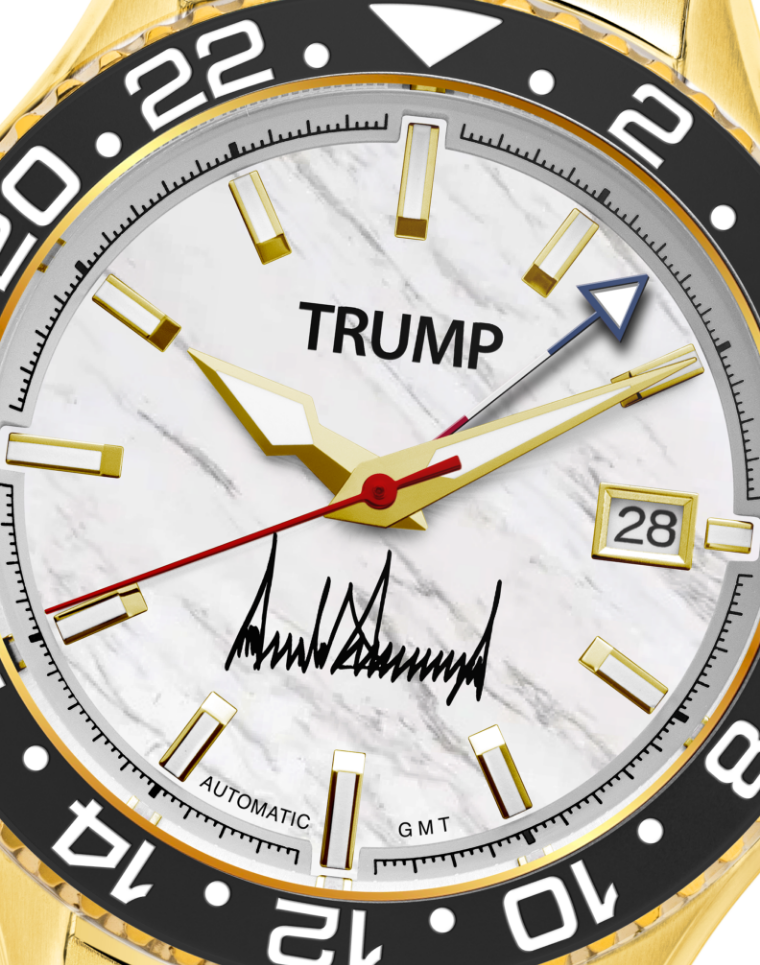 Gold Trump wristwatch with marble dial, date window, automatic GMT, and signature detail.