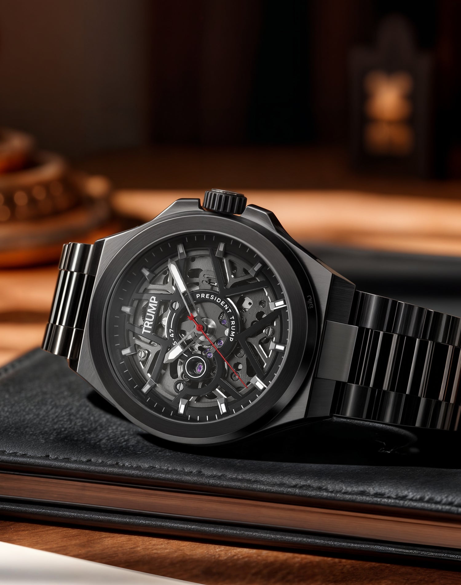Black metal skeleton watch with visible gears, labeled "President Trump," on leather notebook.