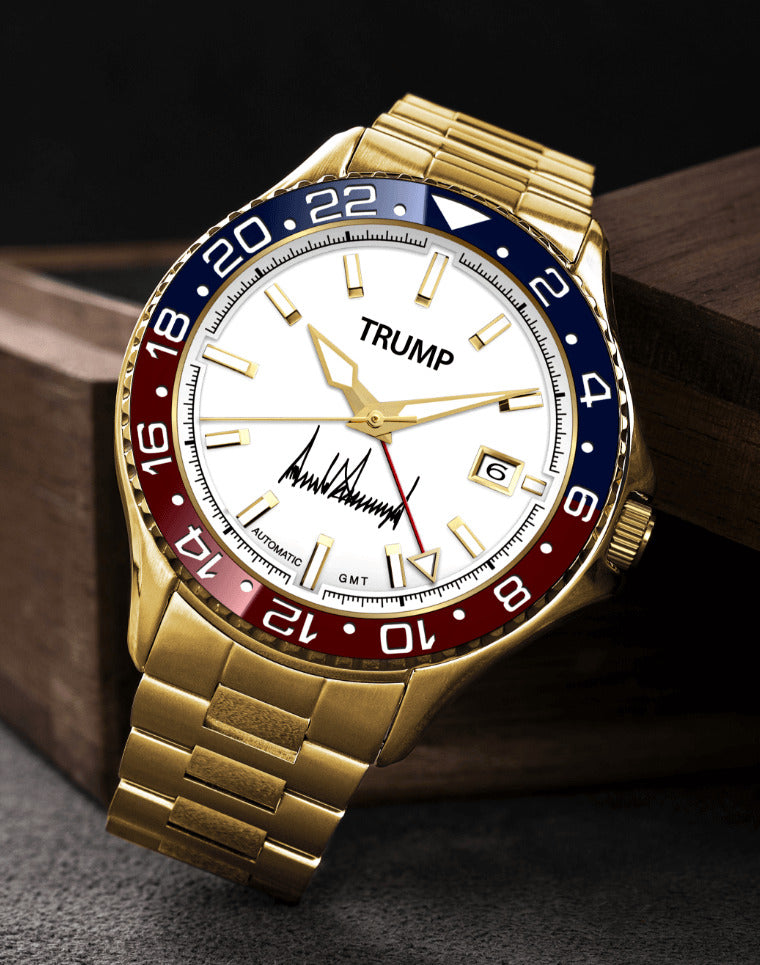 Gold wristwatch with TRUMP branding, white dial, red and blue bezel, and gold hour markers.