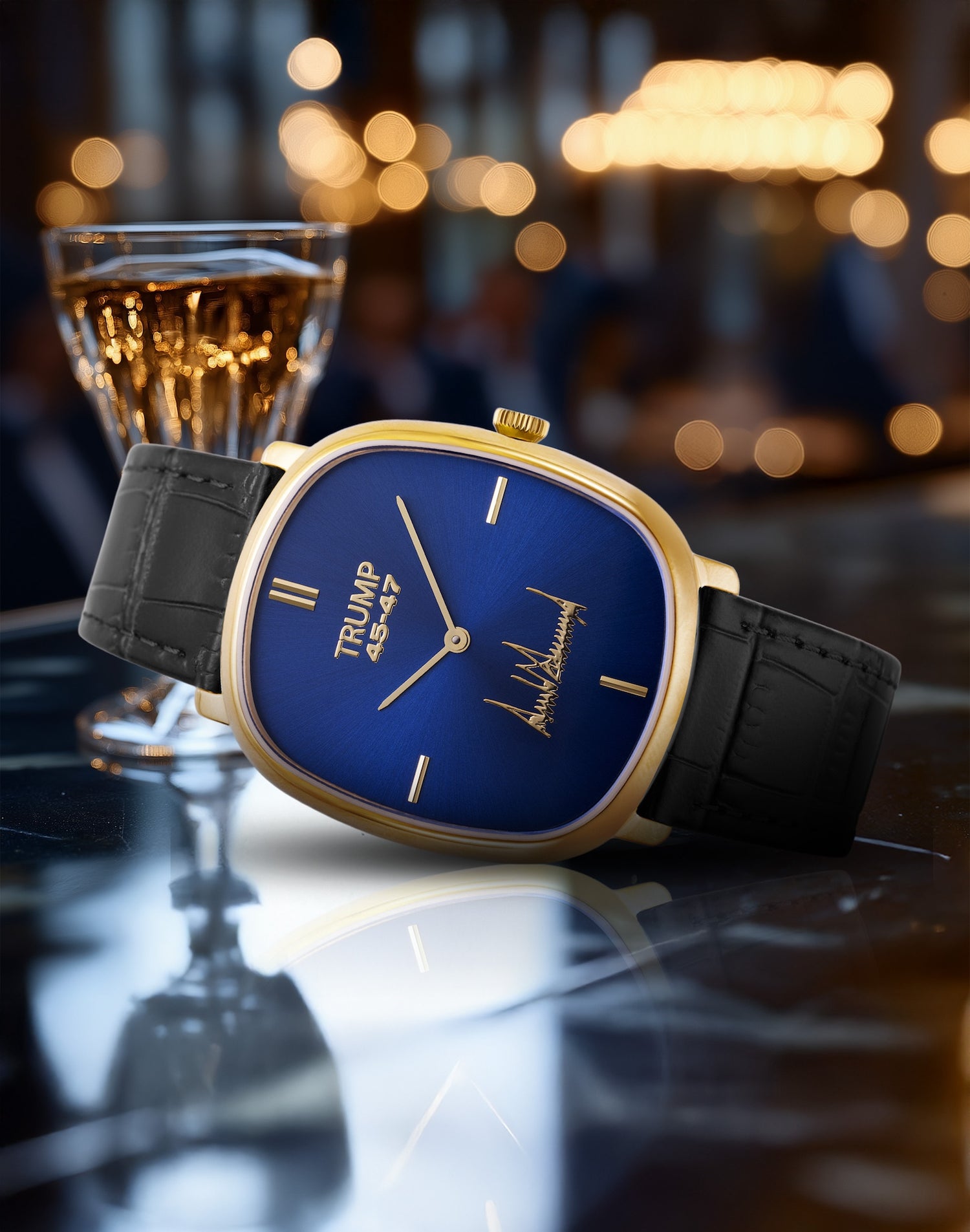 Gold-trimmed blue Trump 45th wristwatch with black leather strap on a reflective table surface.