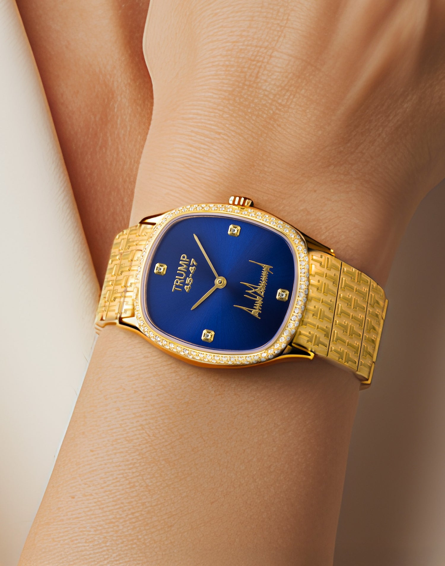 Gold wristwatch with blue dial, diamond bezel, and "Trump 45-47" branding on a person's wrist.