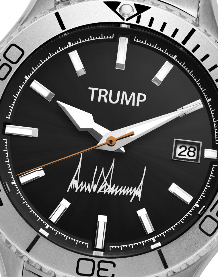 Silver Trump wristwatch with black dial, date display, and signature detail above 6 o’clock.