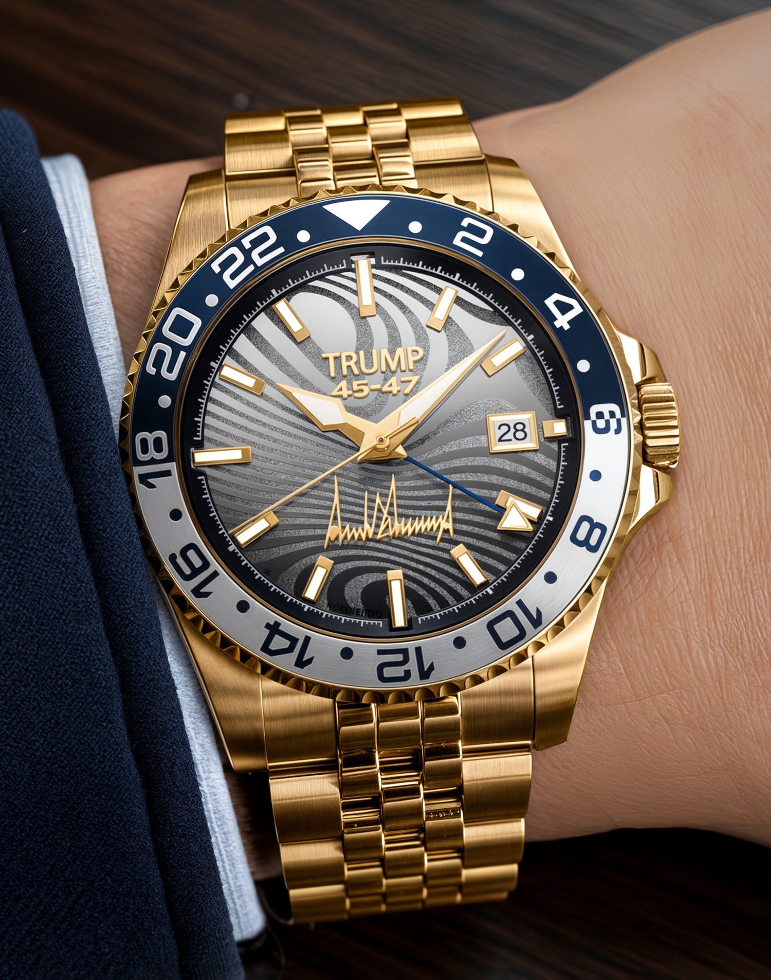 Gold Trump wristwatch with black dial, date display, and signature, worn on wrist in suit.