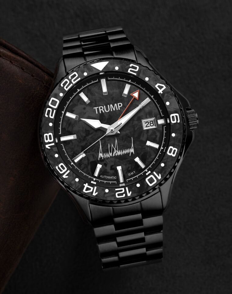 Black Trump-branded GMT automatic wristwatch with carbon fiber dial and metal link bracelet.