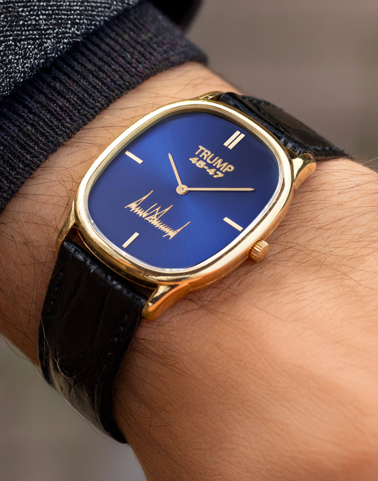 Gold Trump 45-47 wristwatch with blue dial, black leather strap, and signature detail.