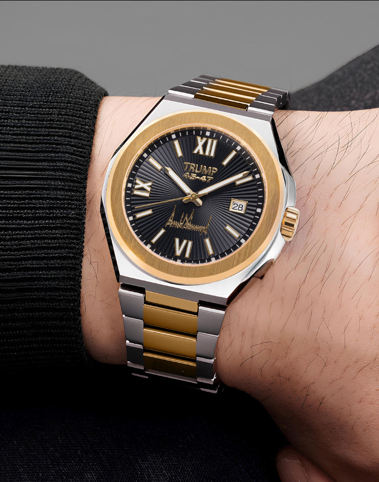 Two-tone gold and silver Trump 45-47 wristwatch with black dial and Roman numerals on wrist.